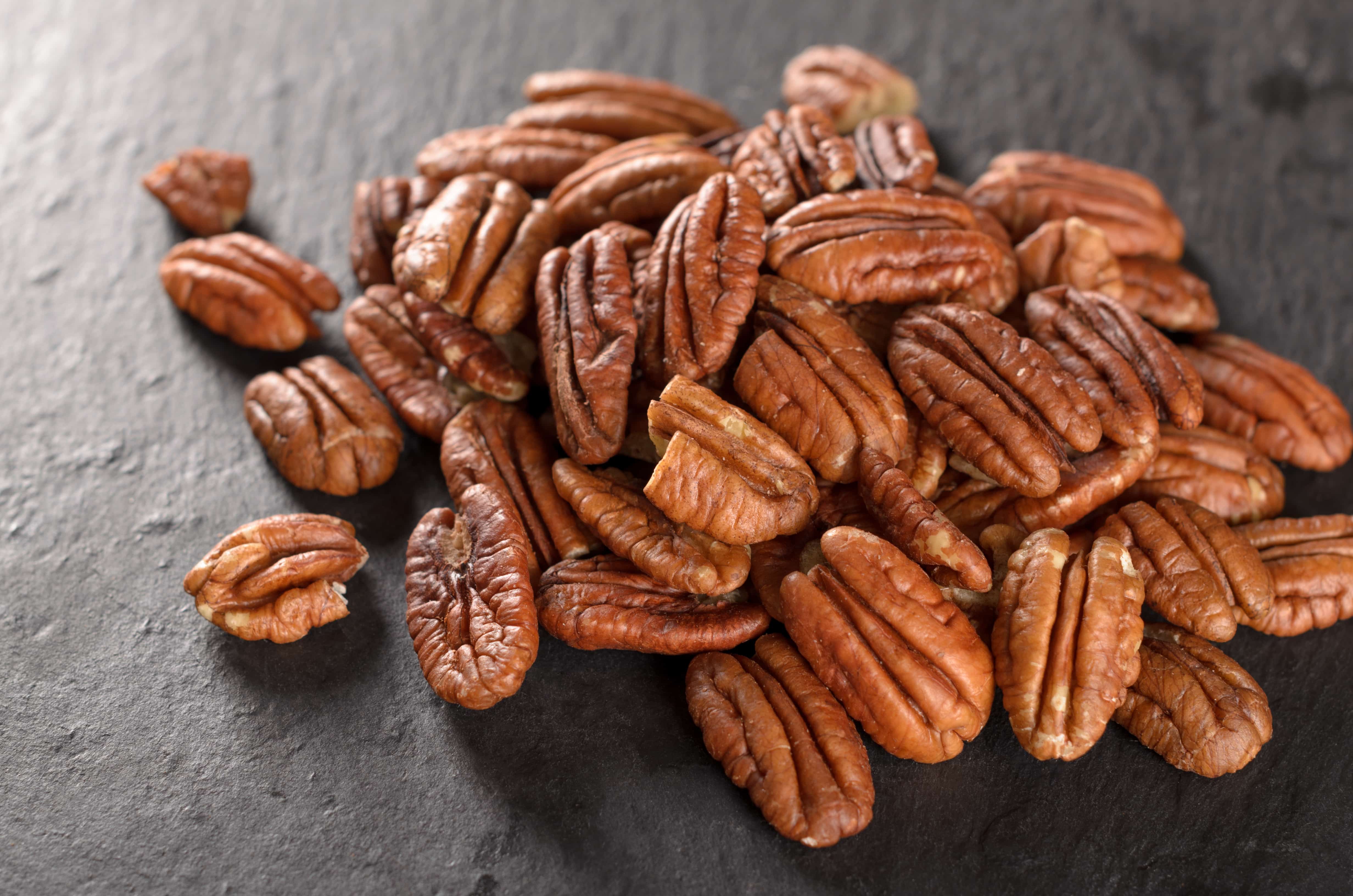 Peeled pecan nuts on a slate plate, selective focus _ ILovePecans